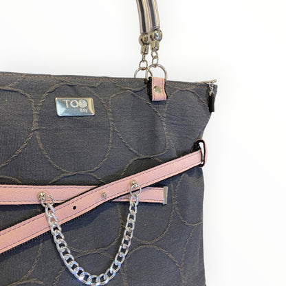 Dettaglio shopper TOOitaly con tessuto circolare in rilievo, finiture in Alcantara rosa e catena metallica decorativa
